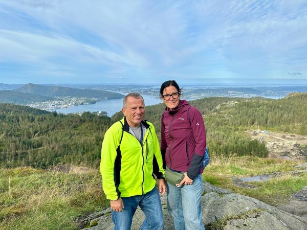 Kathi und Eddy auf einem Felsen hoch über Bergen, im Hintergrund Stadt, Fjord und Inseln.
