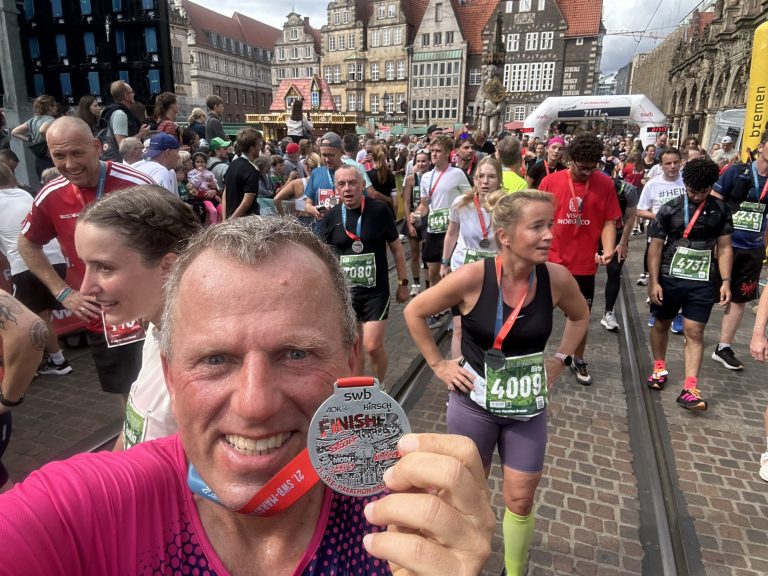 Eduard Andrae hält nach dem Zieleinlauf die Finisher-Medaille des 21. swb-Marathon Bremen in die Kamera